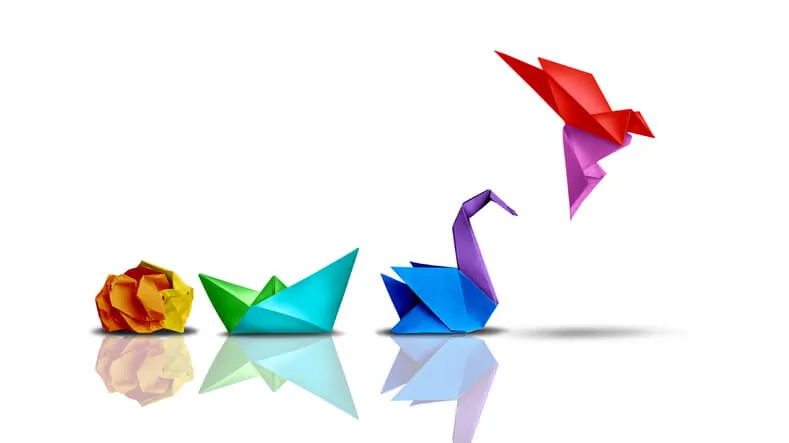 Colorful paper forms progress from a crumpled ball to an origami boat, swan and flying bird on a white background.
