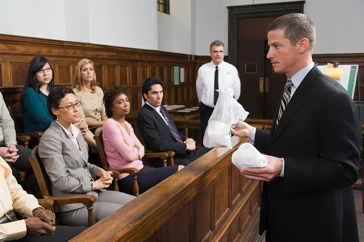 A lawyer presents bagged evidence to a jury in a courtroom.